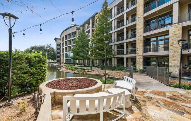 A patio with a fire pit and chairs overlooks a river.