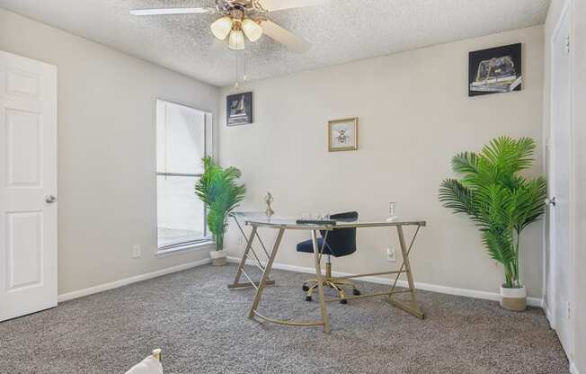 a home office with a desk and a ceiling fan