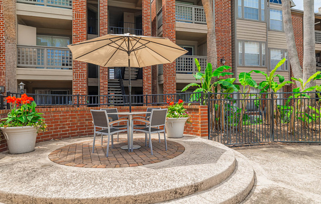 A patio with a table and chairs and an umbrella.