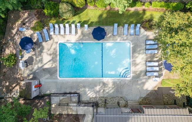 an aerial view of a pool with umbrellas and chairs around it