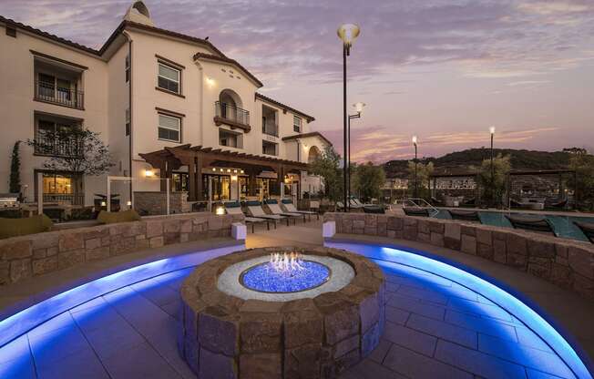 an outdoor fire pit at night with a building in the background