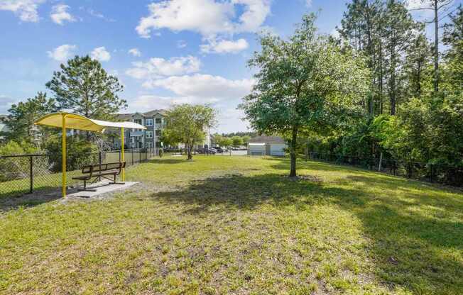 A park with a yellow umbrella and a bench.