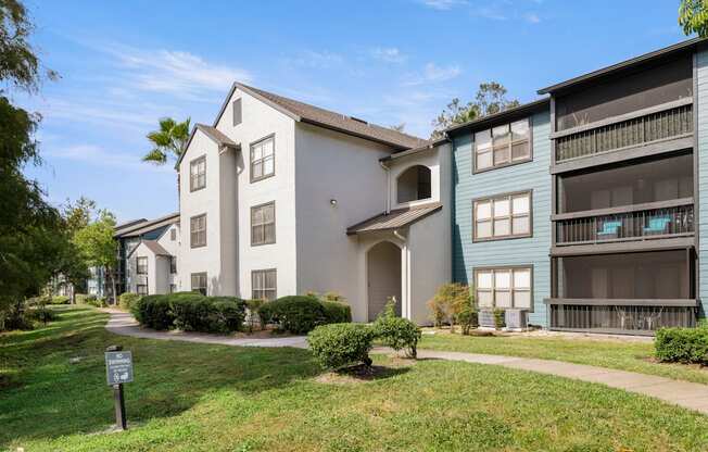 Community apartment building with grass and walking path at Fountains at Lee Vista in Orlando, Florida.