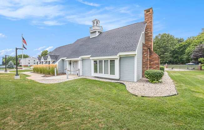 A leasing office with a brick chimney surrounded by a grassy lawn at Apple Ridge Apartments, Michigan, 49534
