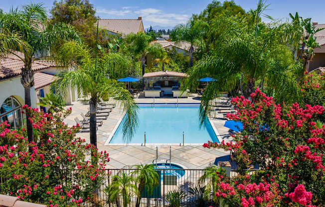 A pool surrounded by palm trees and flowers.