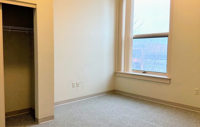 an empty room with a window and a closet