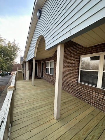 a porch of a brick building with a wooden deck