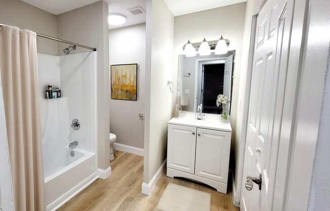 A bathroom with a white cabinet and a mirror above it.