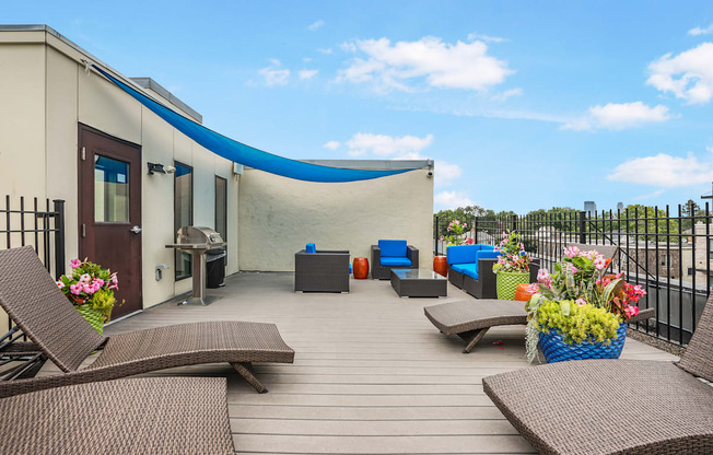 a rooftop deck with chairs and a grill and a blue roof