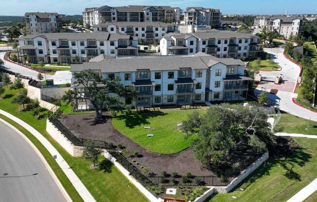 an aerial view of an apartment complex with a green lawn and a road