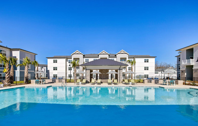 A large swimming pool in front of a building with a clear blue sky above.