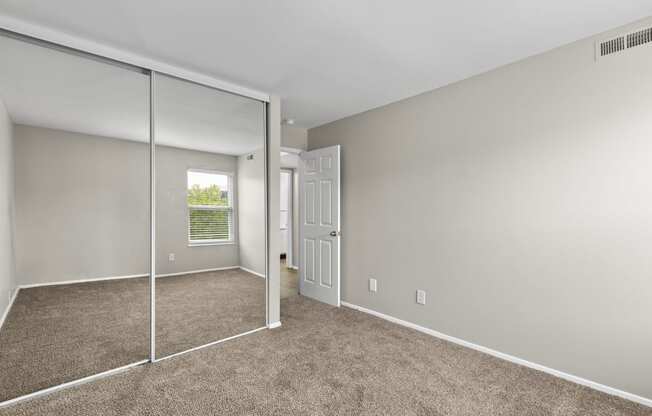 Bedroom with a mirrored closet and carpeted floors at Creve Coeur, Creve Coeur, MO