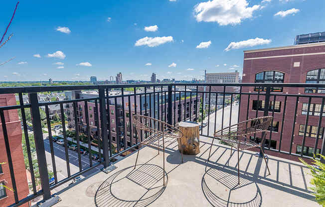 balcony with a view of downtown on a sky-blue day with two wire metal chairs