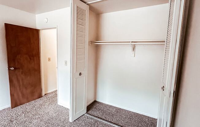 A white closet with a brown door is open.