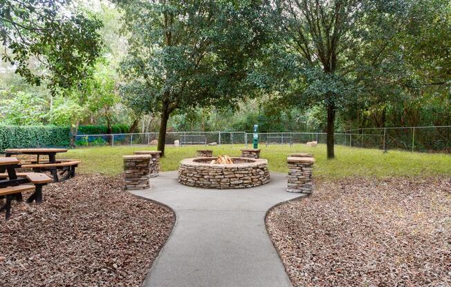 A park with a circular stone structure in the middle of a gravel path.