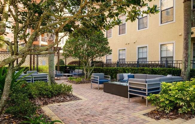 a courtyard with couches and chairs in front of an apartment building