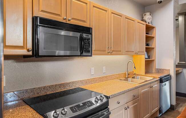 A black microwave is on top of a black stove.