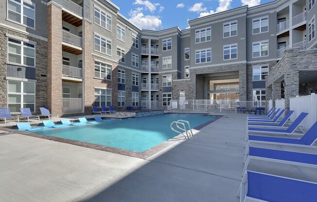 A large swimming pool is surrounded by apartment buildings.
