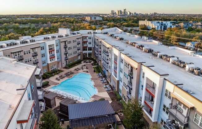 A large apartment complex with a swimming pool in the middle of the courtyard.