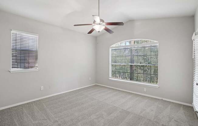 A room with a ceiling fan and a window with blinds.