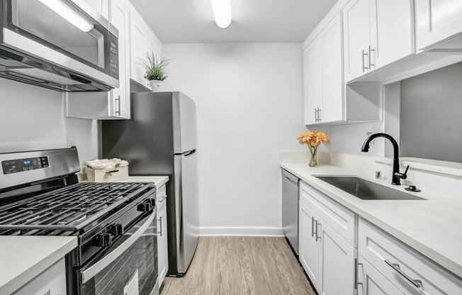 a white kitchen with stainless steel appliances and white cabinets