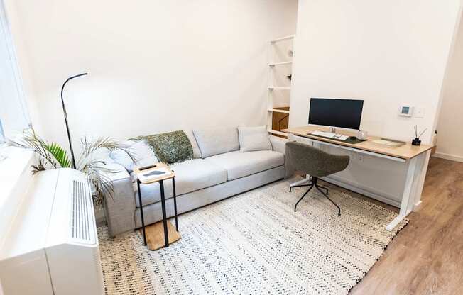 a living room with a couch and a desk with a computer