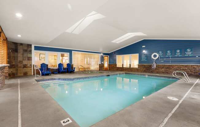 a swimming pool with blue chairs and a blue wall with a water feature