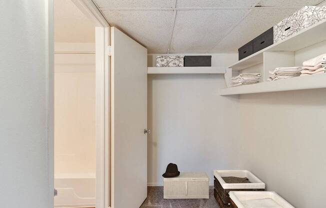 A small room with a white door and a white bench with a black hat on it.