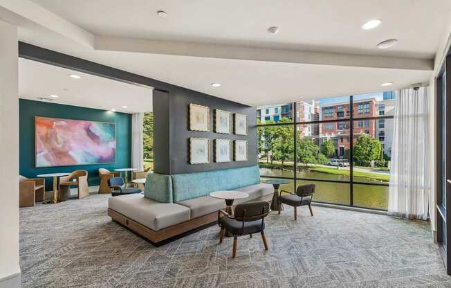 A living room with a grey carpet and a large painting on the wall.