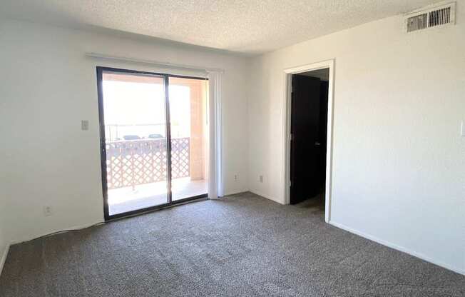A room with a carpeted floor and a sliding glass door.