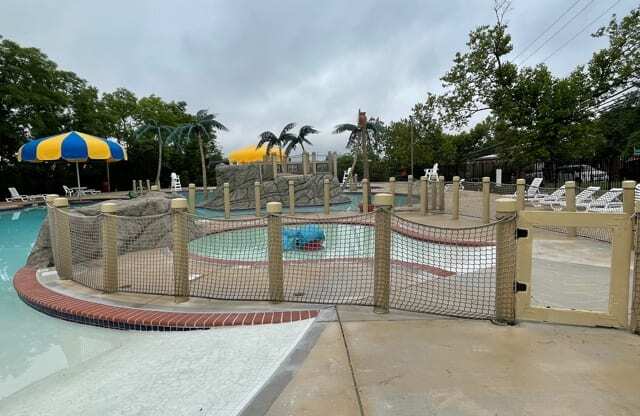 A pool area with a fence and a water slide.