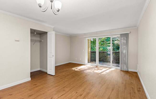 A room with wooden floors and a sliding glass door leading to a balcony.