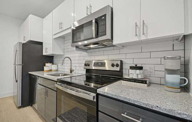 a modern kitchen with stainless steel appliances and granite counter tops at Link Apartments® Calyx, North Carolina, 27517