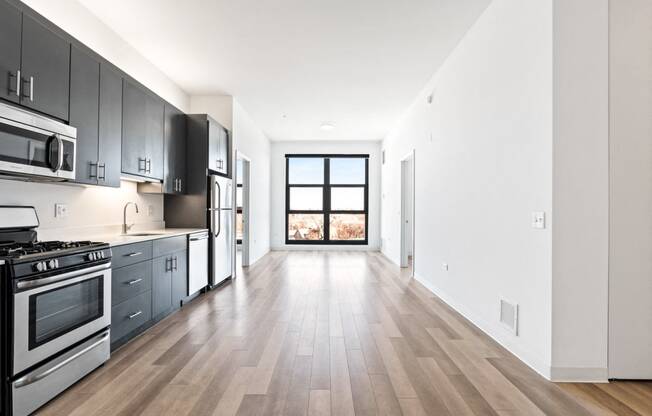 an empty kitchen with stainless steel appliances and wooden floors