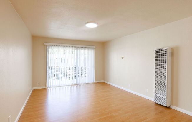 an empty living room with wood flooring and a window