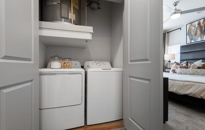 a white washer and dryer in a room next to a bedroom