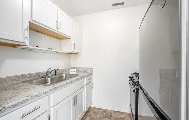 A kitchen with white cabinets and a granite countertop.