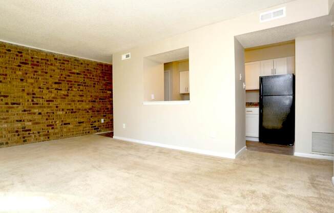 A room with a brick wall and a black fridge.