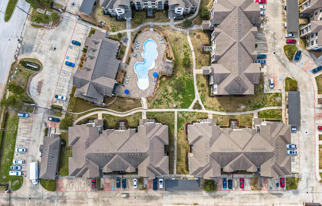 A bird's eye view of a residential area with houses and a swimming pool.