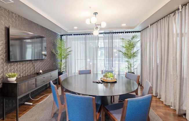 A dining room with a round table surrounded by chairs.