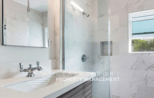 a bathroom with a shower and a sink and a mirror