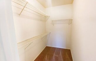 a walk in closet with shelves and a white wall