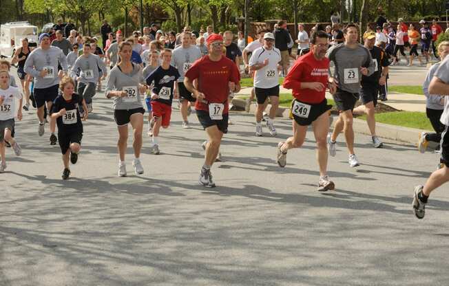 A large group of marathon runners jogging on a tree-lined street near Claremont on the Square Apartments in Exton, PA.