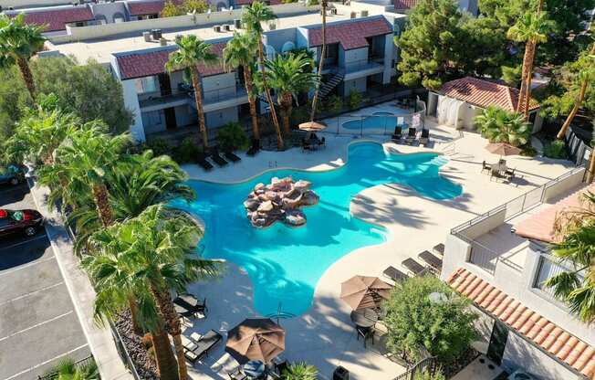 A pool surrounded by palm trees and umbrellas.