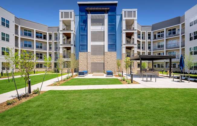 an exterior view of an apartment building with a lawn and picnic area