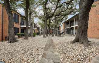 Stone walkway surrounded by trees and apartment buildings at Westdale Pointe in Austin, TX
