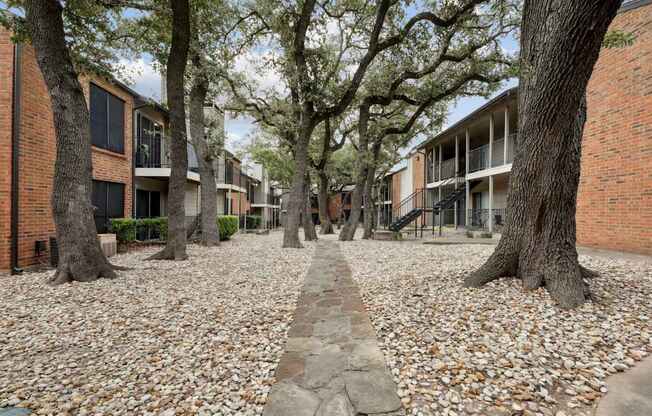 Stone walkway surrounded by trees and apartment buildings at Westdale Pointe in Austin, TX