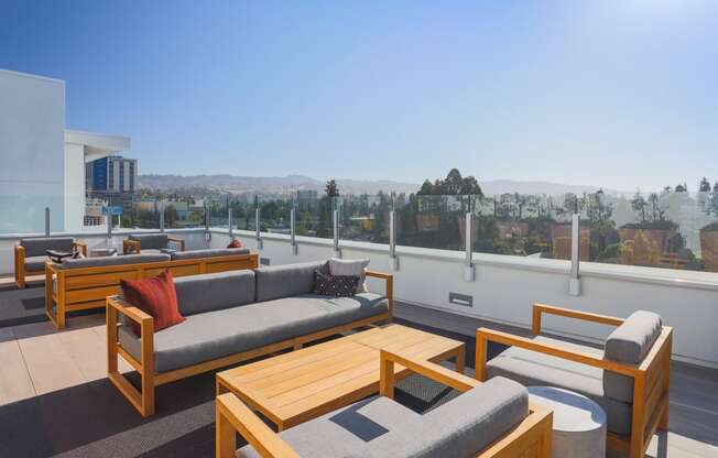 a roof top patio with couches and tables overlooking a city