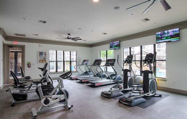 a gym with cardio equipment and flat screen tvs