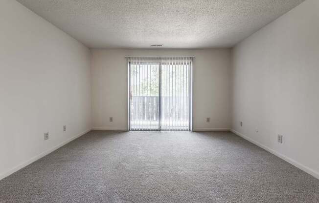 an empty living room with a sliding glass door to a balcony